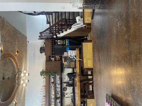Interior of a cosy café with wooden furniture, staircase and shelves of coffee equipment.