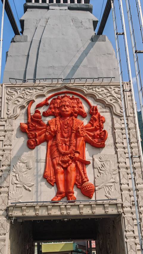 Vivid orange multi-headed Hindu deity relief sculpture on a grey temple wall