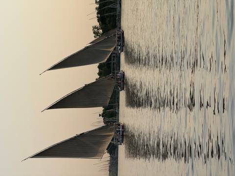 Traditional felucca sailboats gliding across the Nile at sunset casting long reflections on the water