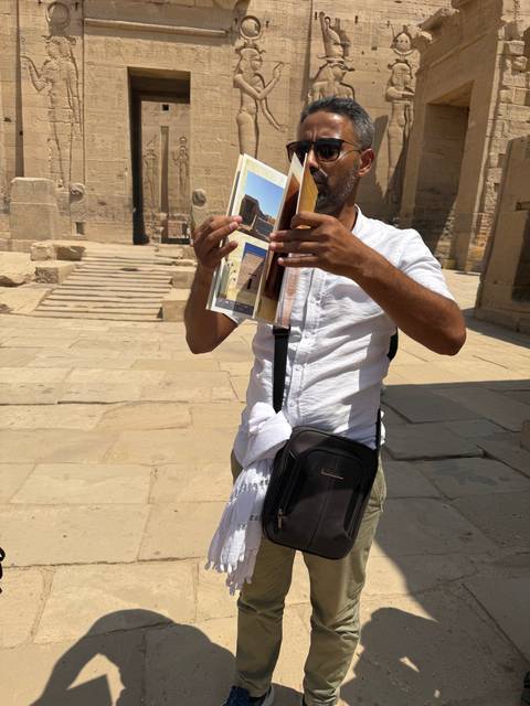 Guide holding up illustrative photos while explaining details inside an ancient stone temple