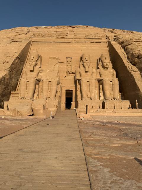 The colossal seated statues of Ramses II at the entrance of Abu Simbel bathed in strong sunlight.