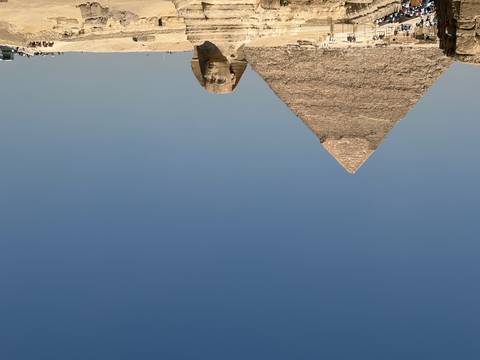 Iconic Great Pyramid of Giza and the Sphinx beneath a clear blue desert sky.