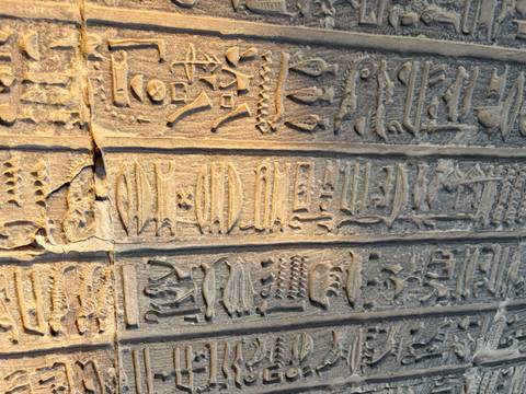 Detail of weathered hieroglyphic columns bathed in warm evening light.
