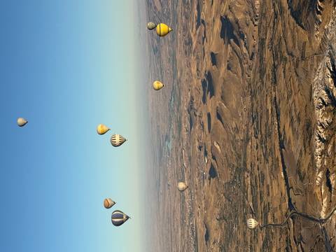 Dozens of hot air balloons floating over Cappadocia’s ochre landscape at dawn
