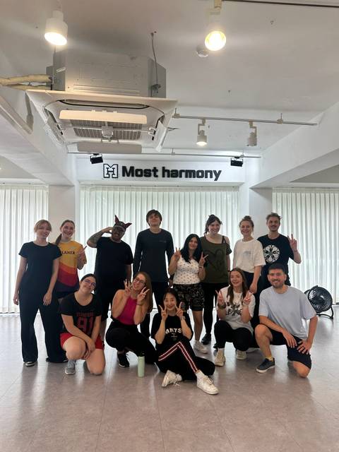 Large group posing together in a bright studio beneath a 'Most harmony' sign