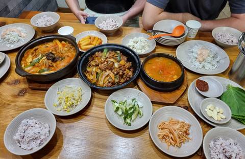 Traditional Korean meal spread of stews, rice and side dishes on wooden table