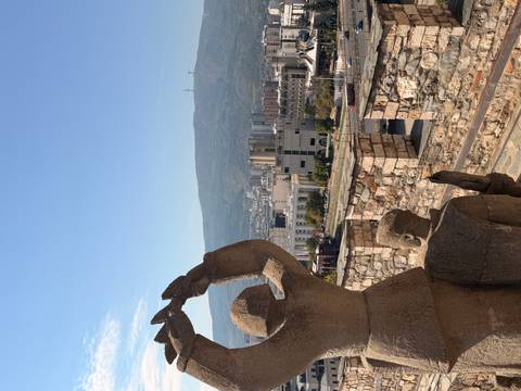 Stone statues overlooking the cityscape of Skopje with mountains in the background on a clear day