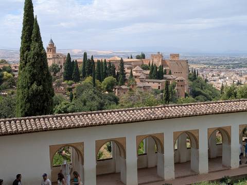 Panoramic view of the Alhambra complex set amid cypress trees overlooking the city of Granada.