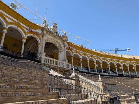 The curved rows of arches inside Seville’s historic bullring under a clear blue sky.