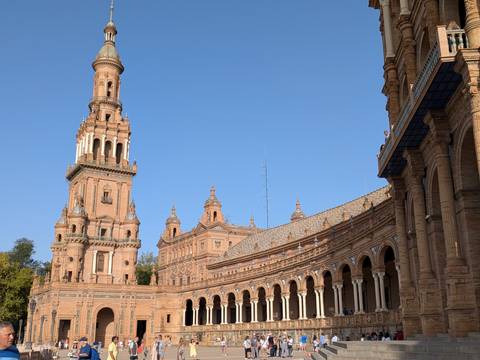 Seville’s Plaza de España tower and sweeping colonnade glowing in late afternoon light against a clear sky.