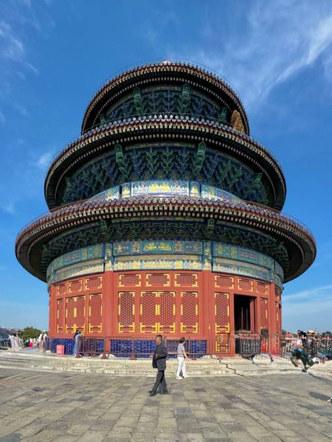 Vibrantly painted circular Hall of Prayer for Good Harvests rising against a clear blue sky.