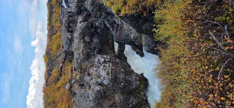 Rocky lava field canyon with milky white river rushing through autumn foliage
