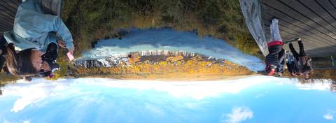 Panoramic view of a blue river and waterfall winding through colorful autumn forest
