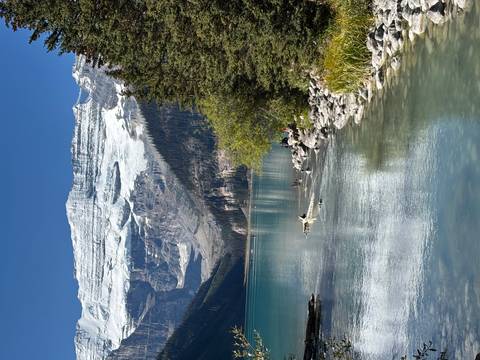 Iconic glacial lake with emerald water reflecting snow-capped peaks and a massive hanging glacier