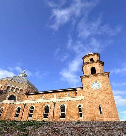 A sandstone church dome and clock tower contrast sharply against a vivid blue sky.