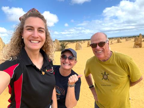 Smiling trio take a selfie amid the yellow sand and limestone spires of the Pinnacles Desert.