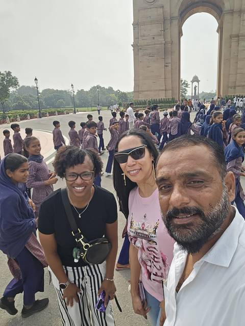 Selfie-style photo with two women and their guide amid a large group of uniformed schoolchildren on a city plaza.