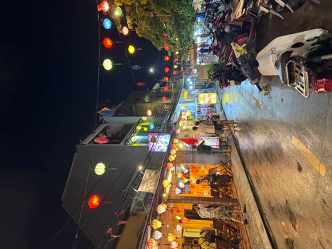 Rain-slicked street lined with colorful lanterns and shops in historic old town at night