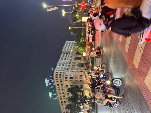 Bustling night traffic scene with dozens of motorbikes speeding past city lights and buildings.