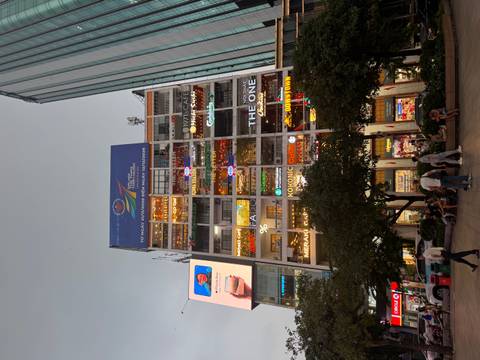 Multi-storey ‘Cafe Apartment’ building covered in colourful neon signs against the evening sky.