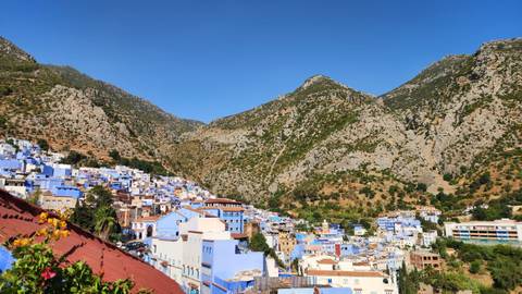 Hillside view of Chefchaouen with clusters of blue houses set against rugged mountains.