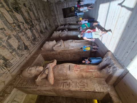 Interior hall of Abu Simbel with colossal carved statues and visiting tourists.
