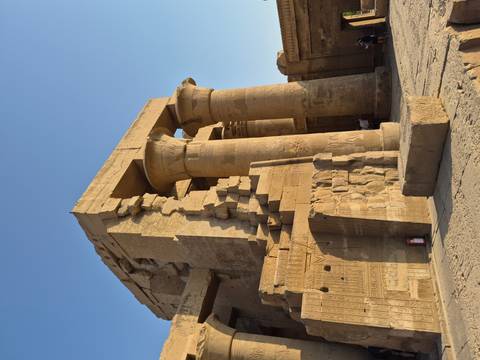 Sunlit columns and battered walls of Kom Ombo Temple with clear evening sky.