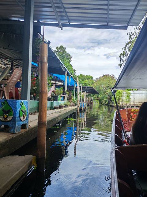 Canal with houses and vegetation reflected on calm water under a partly cloudy sky