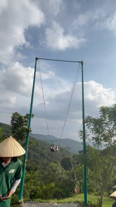 Vertical shot of green suspension bridge towers reaching to sky with clouds, partial composition