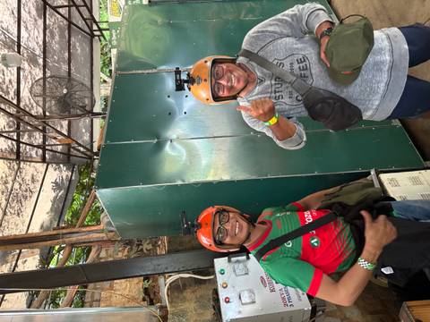 Two men wearing orange helmets and GoPro mounts smiling indoors at adventure venue