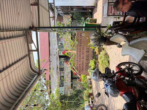Courtyard entrance of Cuong Hoan Silk Factory with a motorbike, potted plants and signage under a metal roof