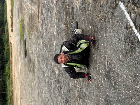 Smiling motorbiker lying playfully on a cracked asphalt surface wearing safety gear
