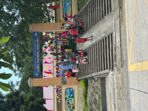Group of school children gathered on steps outside a primary school decorated with colorful bunting