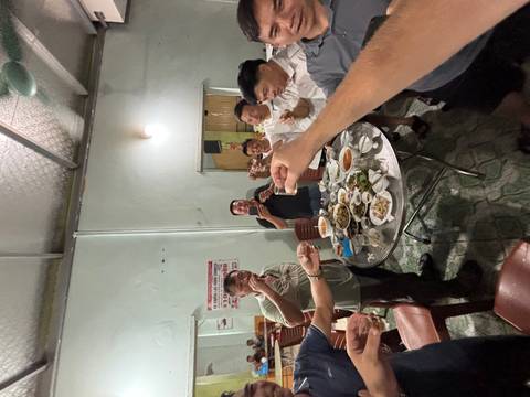 Group of men standing around a dinner table toasting with small glasses in a local restaurant