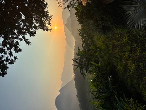Golden sunrise over misty valleys and terraced fields framed by distant mountain silhouettes