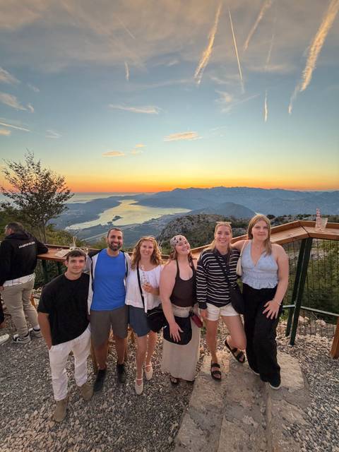 Friends enjoy sunset drinks at a mountain viewpoint overlooking Kotor Bay’s dramatic coastline.