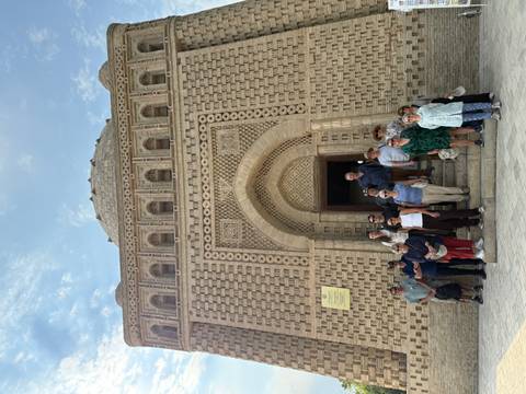 Visitors pose in front of the intricately patterned Samanid Mausoleum’s grand arched entrance in Bukhara.