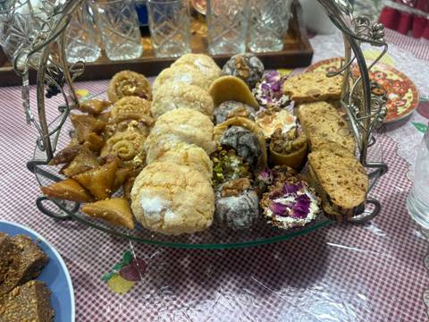 Glass platter filled with assorted Moroccan pastries, cookies and sweets on a patterned tablecloth.