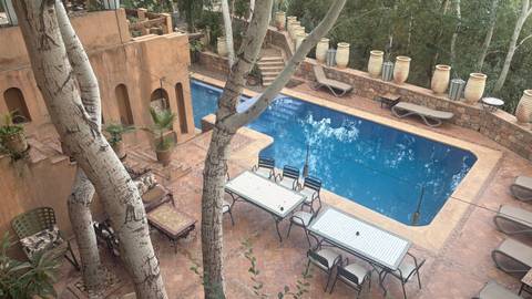 Terracotta-walled boutique hotel courtyard featuring a narrow swimming pool, sun loungers and tall birch trees.