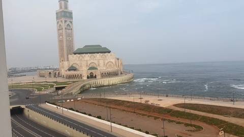Coastal view of the grand Hassan II Mosque jutting into the Atlantic with waves crashing below.