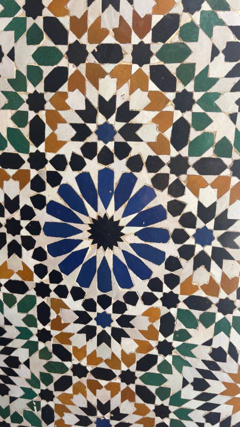 Close-up of traditional Moroccan mosaic tilework forming a blue starburst pattern.