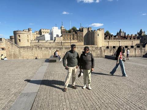 Two travelers standing outside the Tower of London walls on a sunny afternoon.