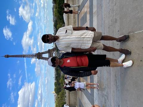 Couple posing on Trocadéro steps with Eiffel Tower rising behind them.