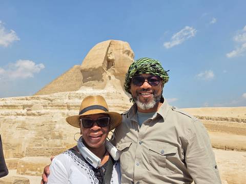 Smiling travelers posing before the Great Sphinx on a bright day.