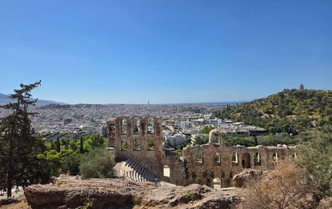 Panoramic view over Athens with the ancient Odeon of Herodes Atticus in the foreground and city stretching to the sea.