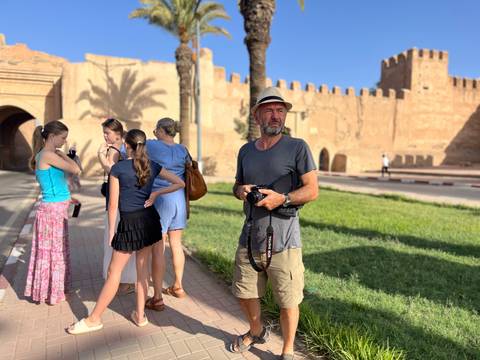 Tourist with camera stands ready while companions chat near the fortified walls of Taroudannt.