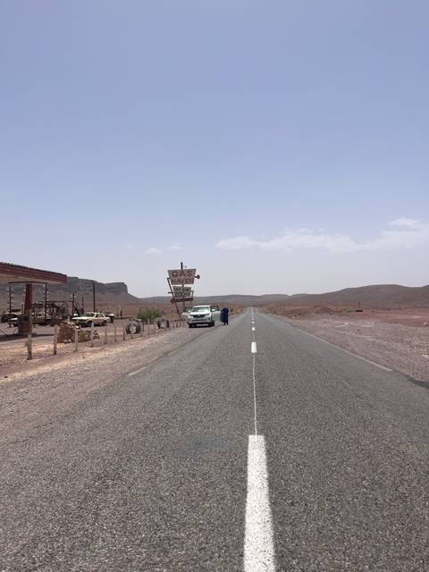Desert highway with a quirky ‘Gas Haven’ sign and isolated service station amid barren hills.