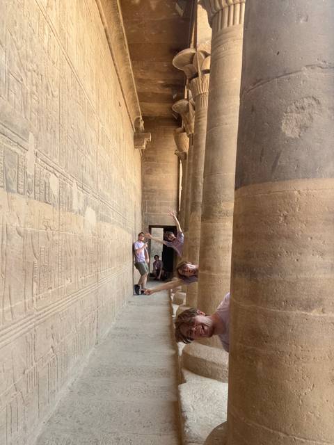 Playful composite shot of a traveller appearing multiple times between ancient stone columns engraved with hieroglyphs.