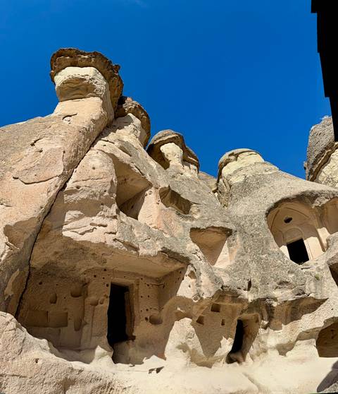 Close-up of Cappadocia fairy-chimney rock formations under a deep blue sky.