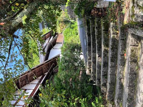 Stone steps leading up to traditional wooden houses framed by lush greenery and blue sky.